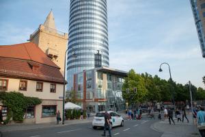 Blick vom Johannisplatz in Richtung Neue Mitte Jena und den Leutragraben, zu sehen sind Fußgänger, die die Straße queren und Fahrradfaher und Autos