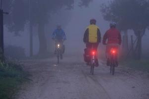 Radfahrende auf einem Weg im Nebel mit Licht