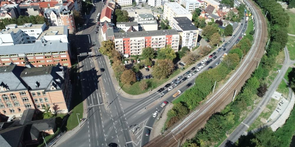 Luftbild von der Kreuzung Stadtrodaer Straße / Am Eisenbahndamm mit Wohnhäusern, Bahnschienen und Bäumen