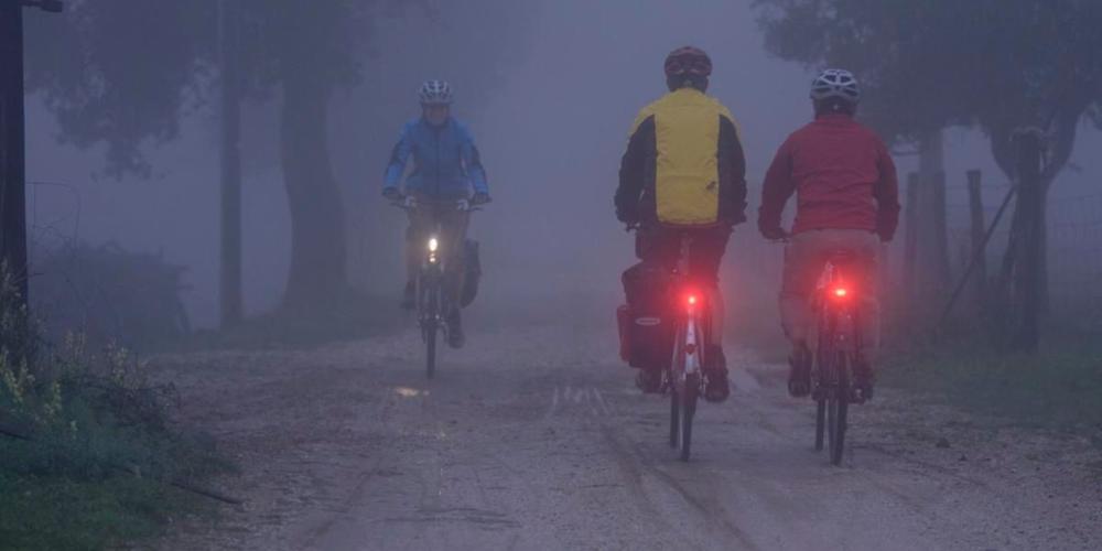 Radfahrende auf einem Weg im Nebel mit Licht