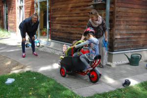 Das neue Kinderfahrzeug wird in der Kita Billy ausprobiert, im Vordergrund fährt ein Kind das Fahrzeug, 2 Erzieher sind zu sehen.