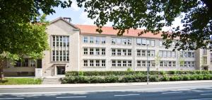 Dienstgebäude Anger 26 - Haupteingang, im Vordergrund Bäume und Straße, blauer Himmel