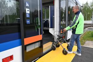 Mann mit neonfarbener Jacke steigt mit Rollator in einen Bus des Jenaer Nahverkehrs ein