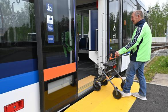 Mann mit neonfarbener Jacke steigt mit Rollator in einen Bus des Jenaer Nahverkehrs ein