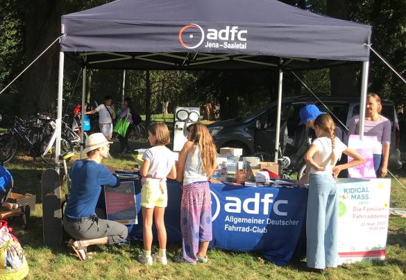 Infostand mit Pavillion, ADFC-Logo, Erwachsene und Kinder stehen um den Stand herum
