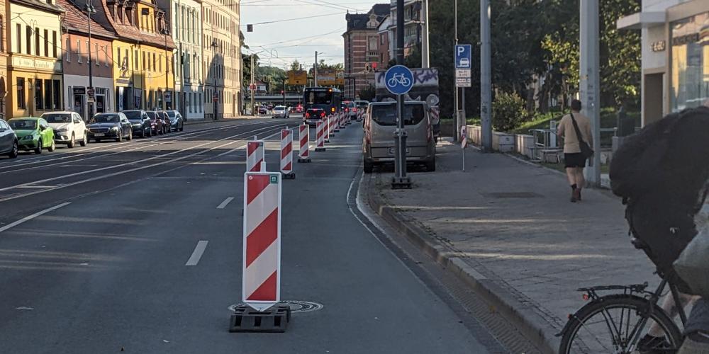 Bild vom Popup-Radweg im Löbdergraben Jena, abgetrennt durch rot-weiße Baken