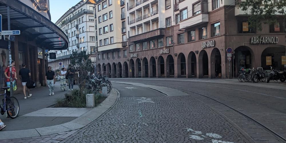 Blick in eine Straße in der Sadt, beidseitig mehrgeschossige Häuser, Kopfsteinpflaster, rechts Straßenbahnschienen, mit weißer Markierung aufgebrachte Radverkehrsführung