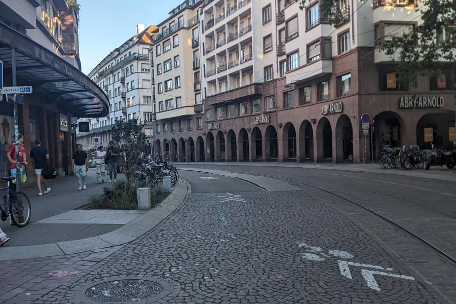 Blick in eine Straße in der Sadt, beidseitig mehrgeschossige Häuser, Kopfsteinpflaster, rechts Straßenbahnschienen, mit weißer Markierung aufgebrachte Radverkehrsführung